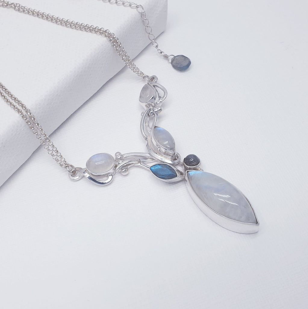 A nature inspired design, this necklace features vine like detailing hand worked in Sterling Silver. A large, marquise Moonstone is the centrepiece, with a further three Moonstones and two Labradorite stones, scattered beautifully across the design. The chain compromises of a double fine Sterling Silver belcher chain, extendable from 16" to 18". Finishing off the design, a Labradorite bead has been added to the end of the extension chain. 