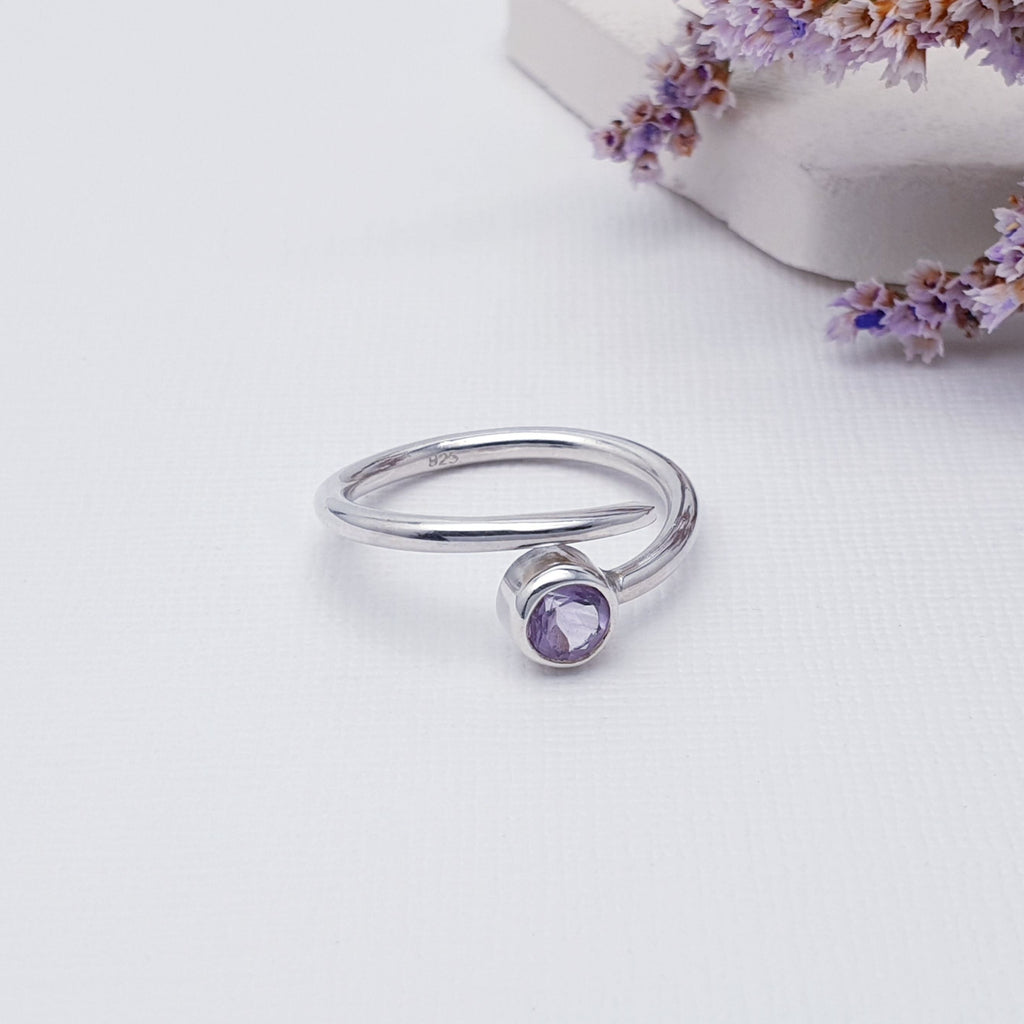 This simple ring features a round, tabletop cut, Amethyst stone in a Sterling silver setting. Open at the front, this little ring wraps elegantly around the finger creating a minimalist and comfortable design, perfect for everyday wear.