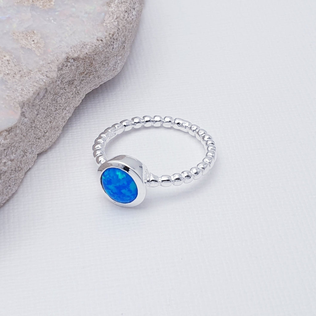 Our Reconstituted Opal Bubble Band Ring is perfect for everyday wear or special occasions.  A beautiful design, this ring features a stunning, round, Reconstituted Opal stone in a simple lowered setting. The band is shaped in a bubble-like ball design, to add extra detailing.