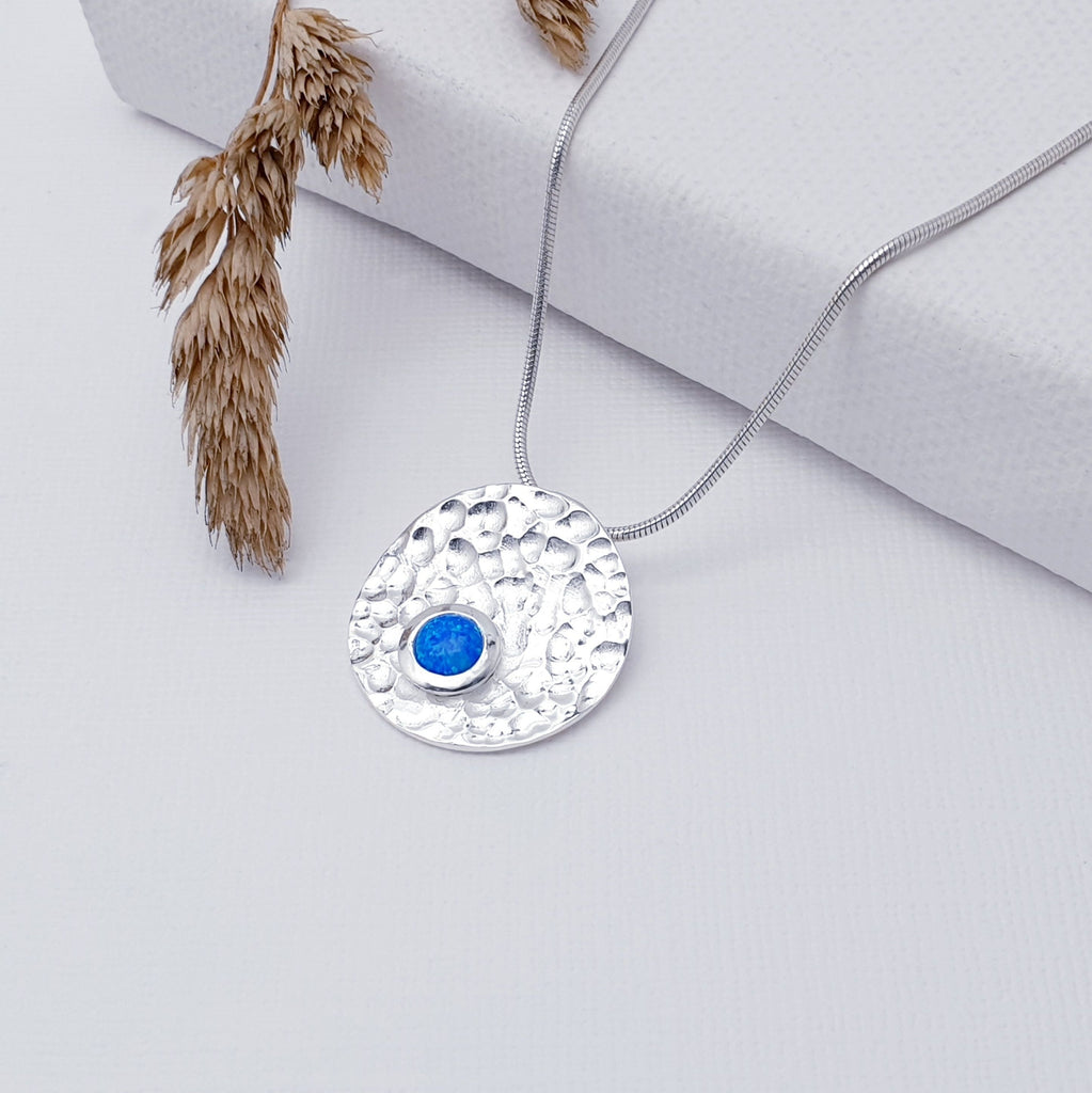Our Reconstituted Opal Sterling Silver Hammered Disk Pendant (chain not included) is so cute and would be perfect for everyday wear.  This stunning pendant features a small, cabochon Reconstituted Opal sitting off-center on a beautiful, hammered Sterling Silver disk.