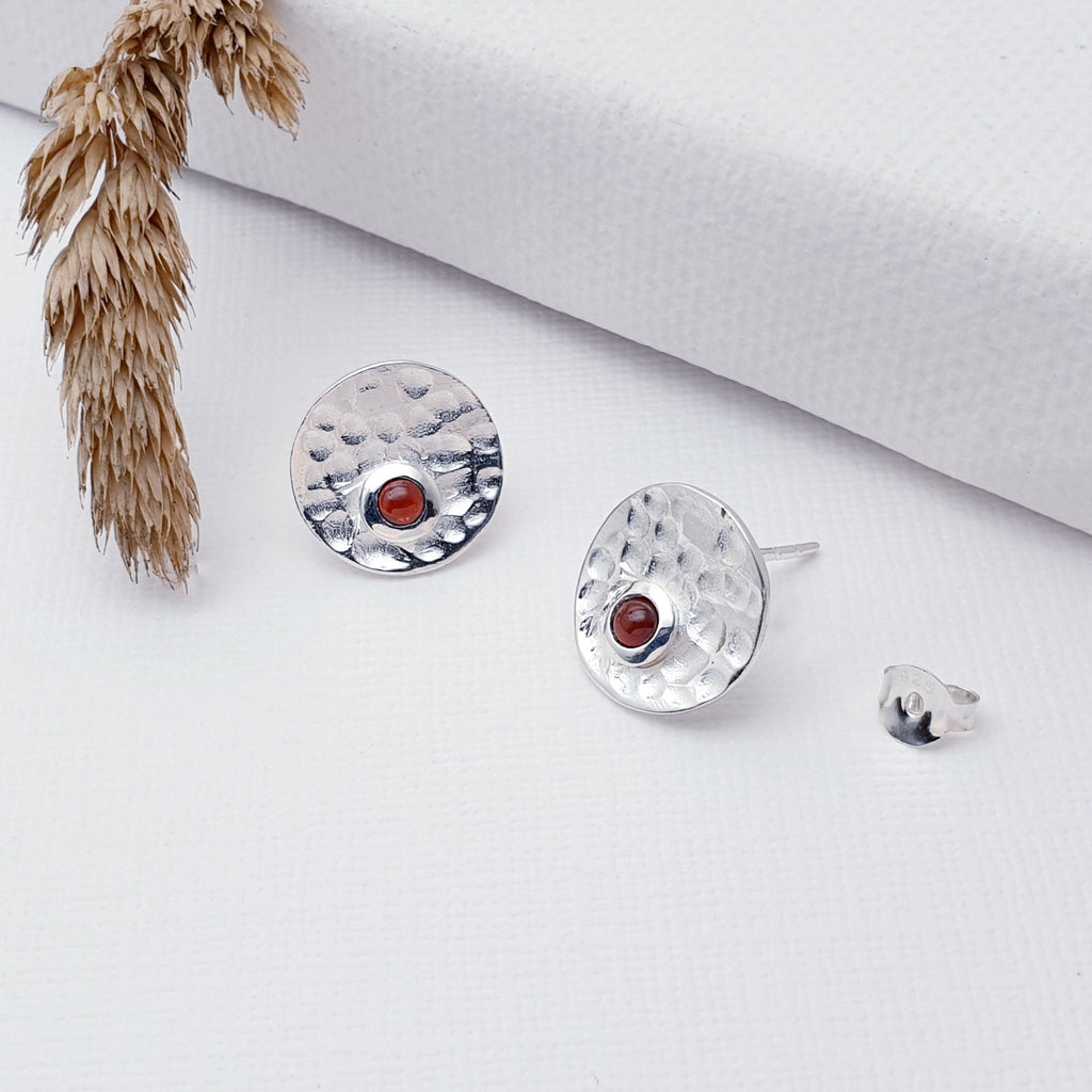 Our Sterling Silver Garnet Hammered Disk Studs are perfect for every day wear.  Sometimes less is more, and that is definitely the case with this gorgeous pair of Garnet studs. These stunning studs feature small, cabochon Garnet's sitting off-center on beautiful, hammered Sterling Silver disks. 